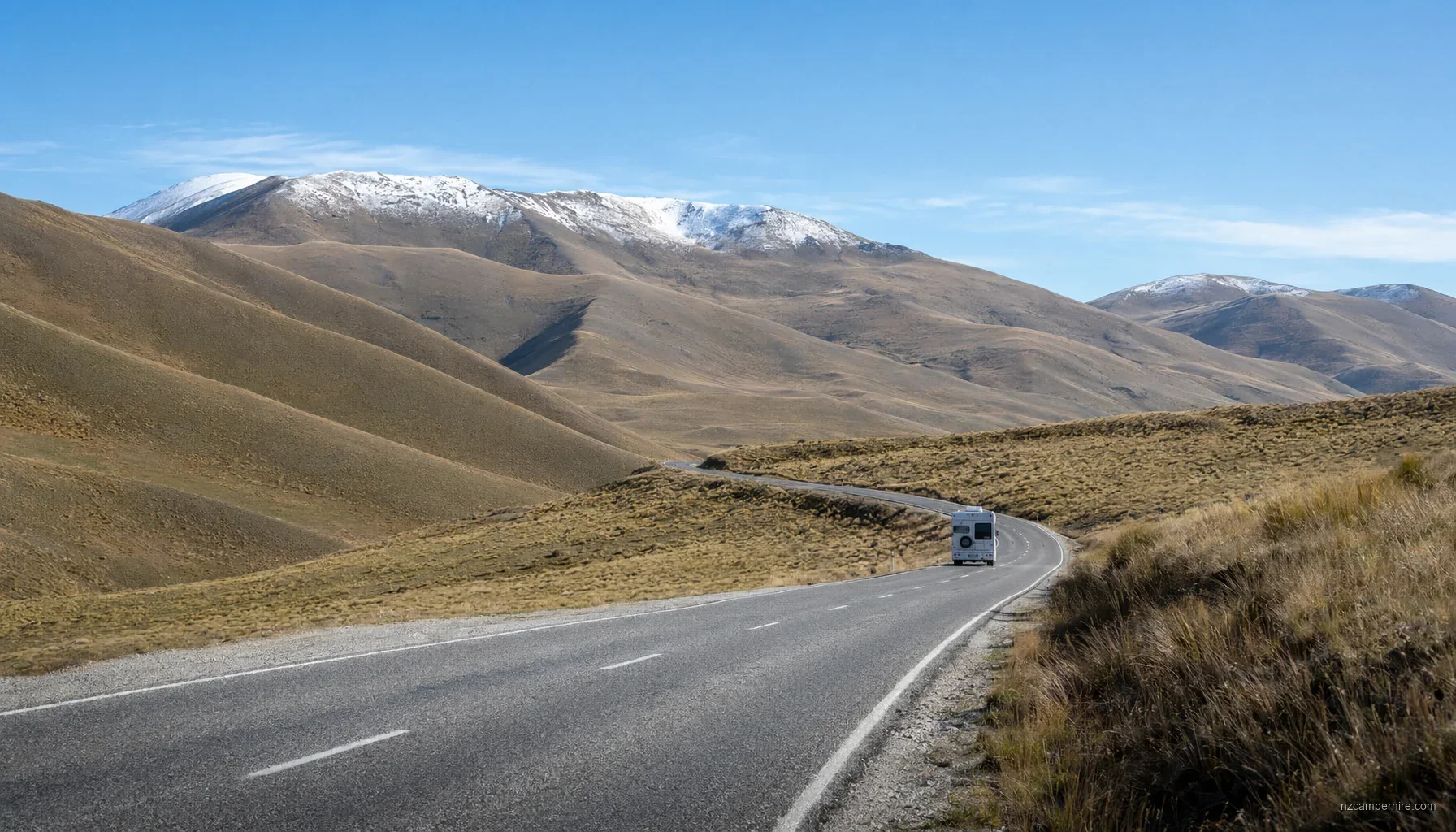Motorhome on a NZ alpine road with mountains in the background