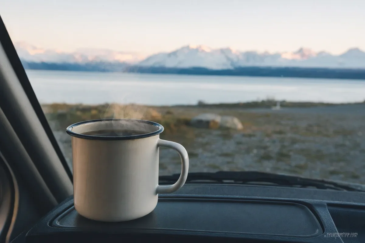 Coffee mug on a campervan dashboard at sunrise